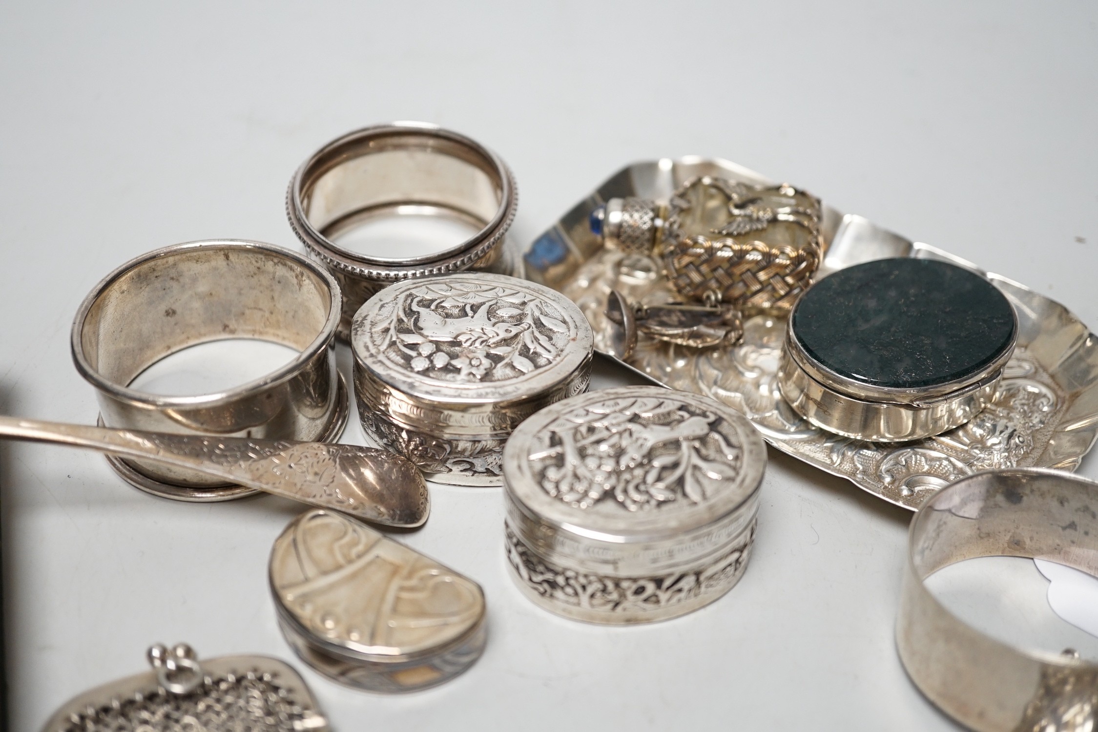 Sundry small silver including four assorted napkin rings, mounted bible, butter knife, pin tray, wine label etc. together with two white metal oval pill boxes, a moss agate mounted oval pill box and scent bottle.